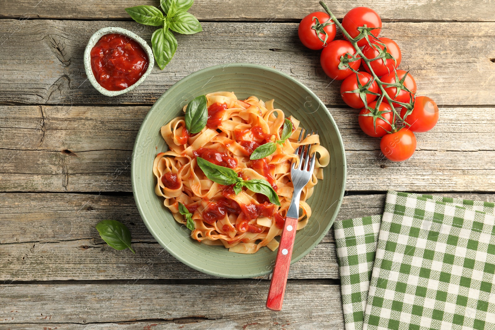 Photo of Delicious pasta with tomato sauce and basil on wooden table, flat lay