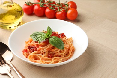 Photo of Delicious pasta with tomato sauce and basil in bowl on wooden table