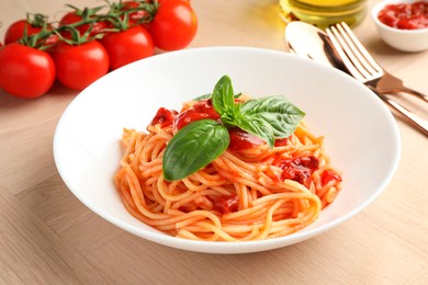 Delicious pasta with tomato sauce and basil in bowl on wooden table, closeup