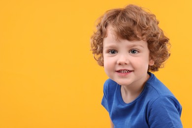 Portrait of cute little boy on yellow background, space for text