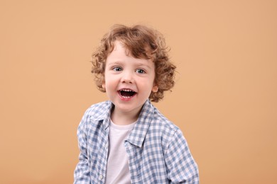 Portrait of cute little boy on beige background