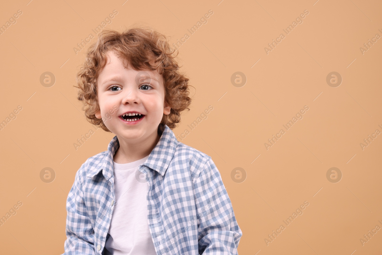 Photo of Portrait of cute little boy on beige background, space for text