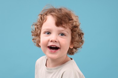 Portrait of cute little boy on light blue background