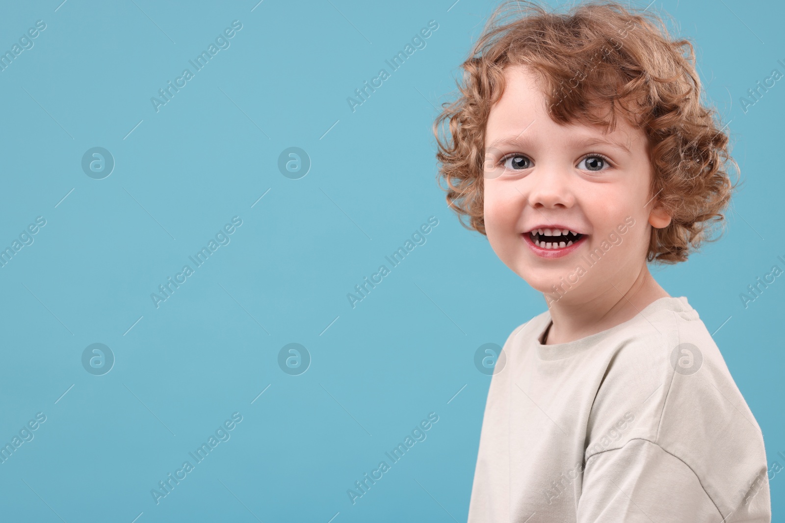 Photo of Portrait of cute little boy on light blue background, space for text