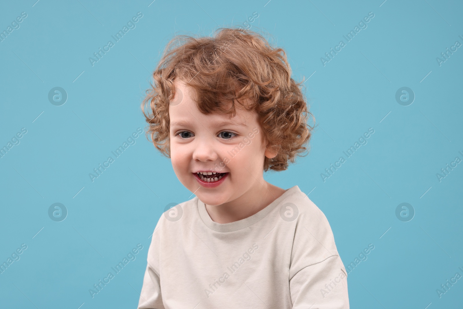 Photo of Portrait of cute little boy on light blue background