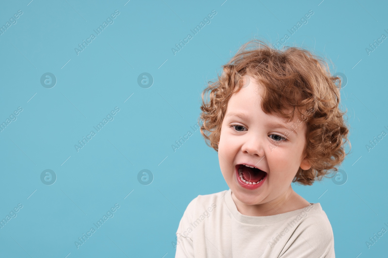 Photo of Portrait of emotional little boy on light blue background, space for text