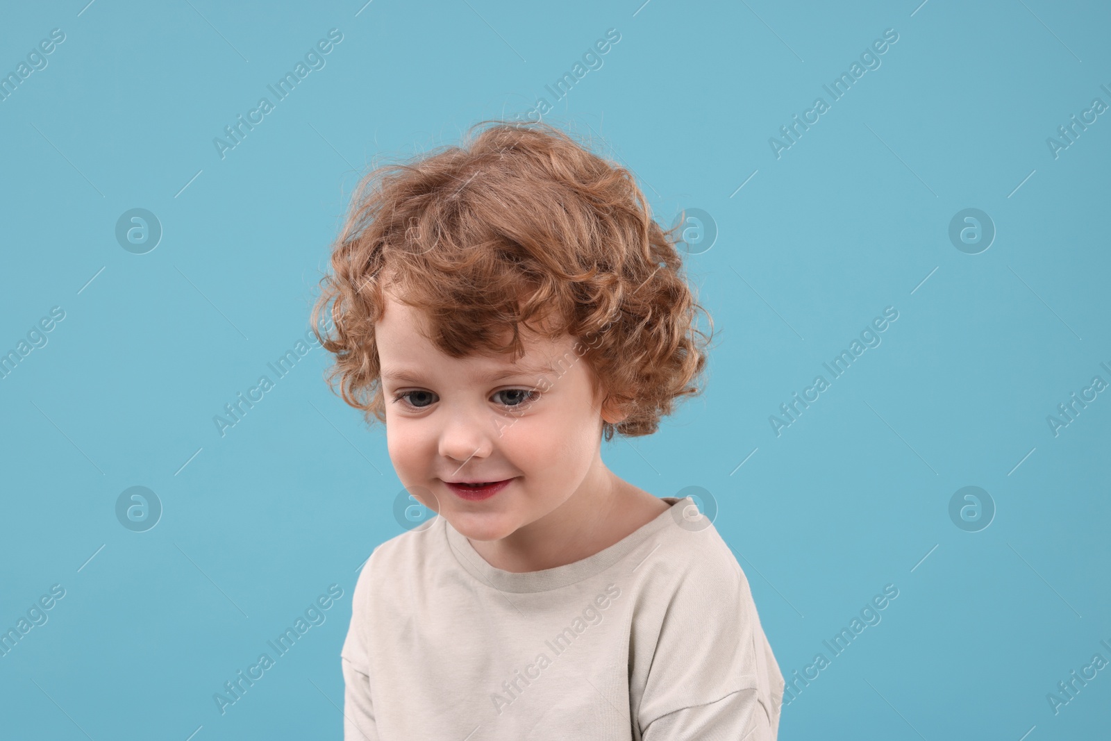 Photo of Portrait of cute little boy on light blue background