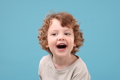 Photo of Portrait of emotional little boy on light blue background