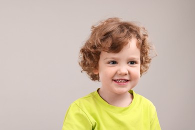 Portrait of cute little boy on grey background, space for text