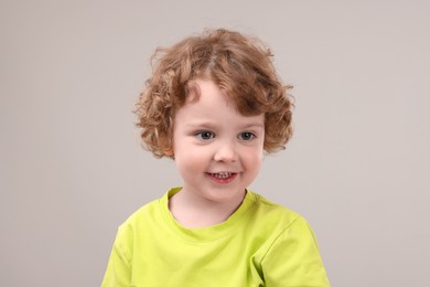 Portrait of cute little boy on grey background