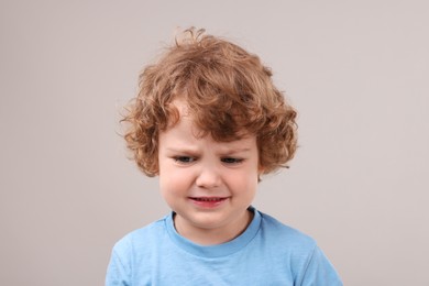 Portrait of sad little boy on grey background