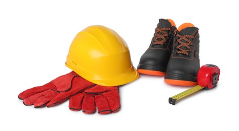 Photo of Pair of working boots, hard hat, protective gloves and measuring tape isolated on white