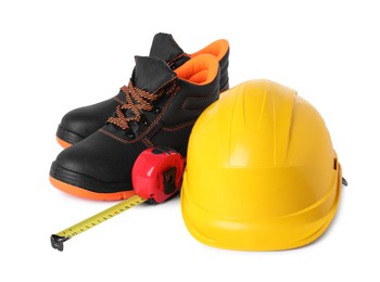 Photo of Pair of working boots, hard hat and tape measure isolated on white