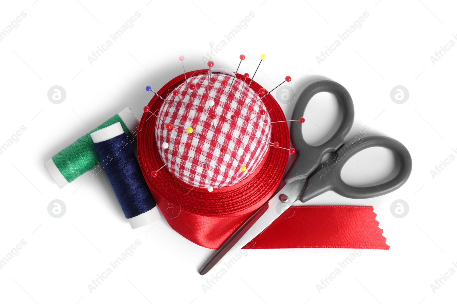 Photo of Checkered pincushion, sewing pins, spools of threads, ribbon and scissors isolated on white, top view