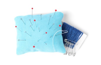 Light blue pincushion with sewing pins and threads isolated on white, top view