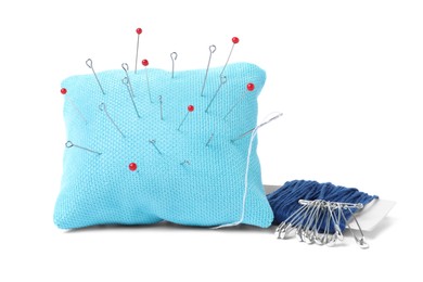 Light blue pincushion with sewing pins and threads isolated on white