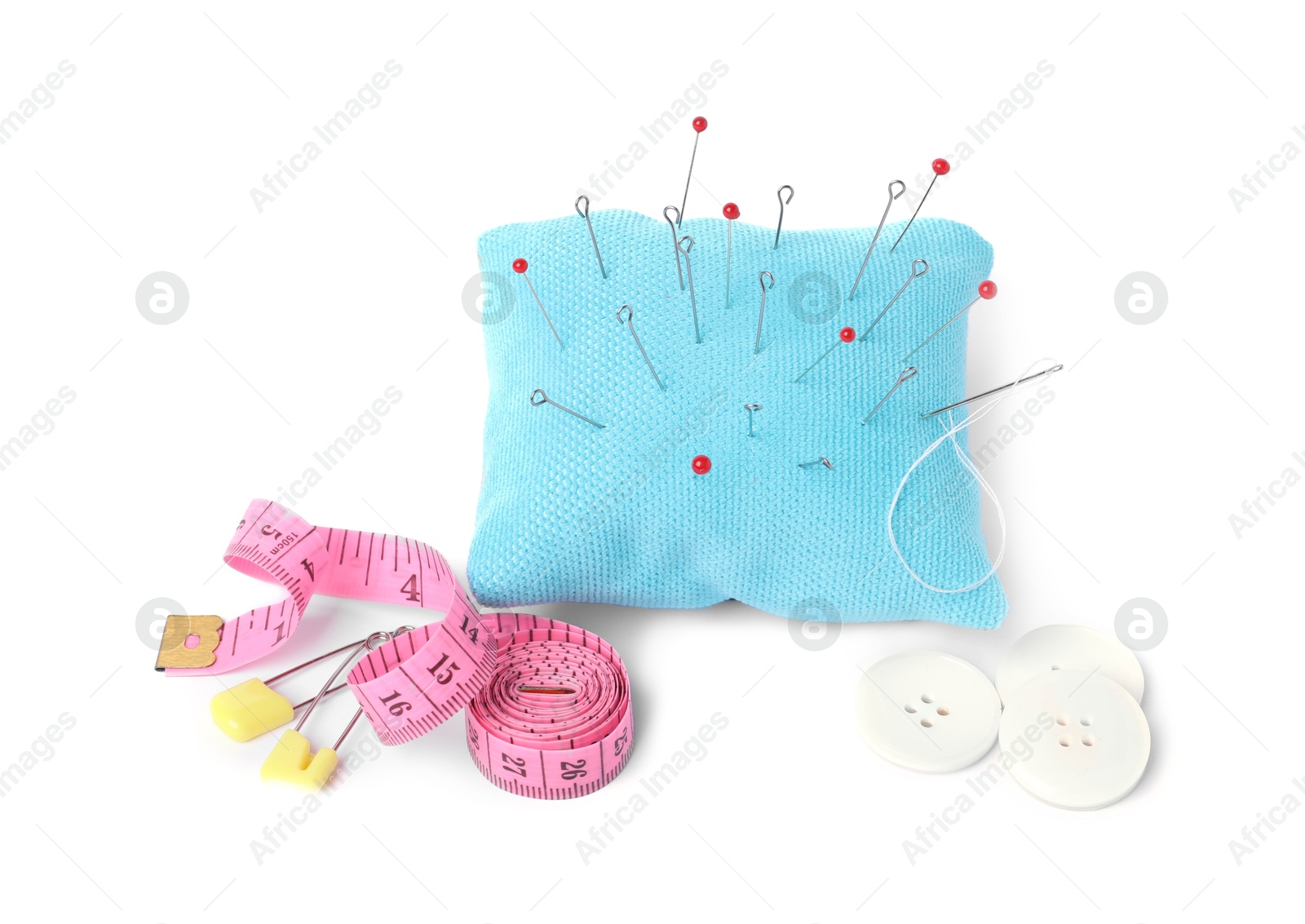 Photo of Light blue pincushion with sewing pins, measuring tape and buttons isolated on white