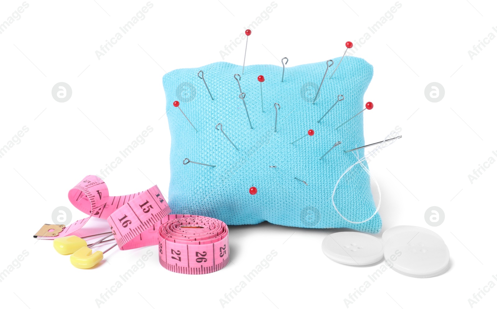 Photo of Light blue pincushion with sewing pins, measuring tape and buttons isolated on white