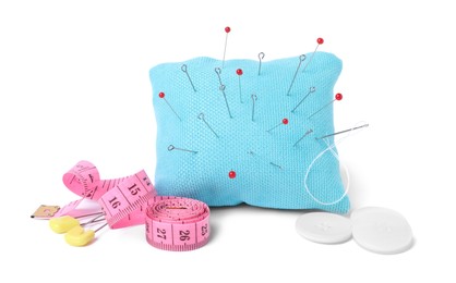 Light blue pincushion with sewing pins, measuring tape and buttons isolated on white