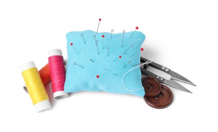 Light blue pincushion with sewing pins, spools of threads, cutter and buttons isolated on white