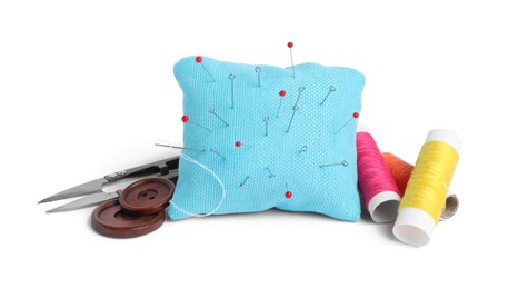 Light blue pincushion with sewing pins, spools of threads, cutter and buttons isolated on white