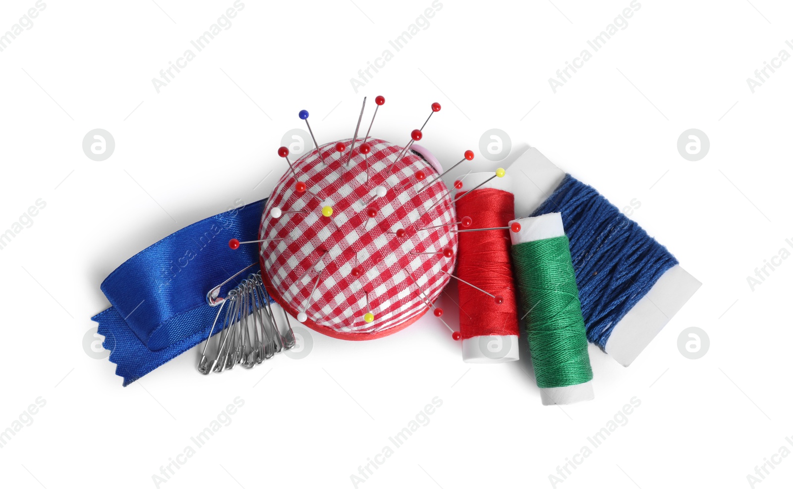 Photo of Checkered pincushion with sewing pins, spools of threads and ribbon isolated on white, top view