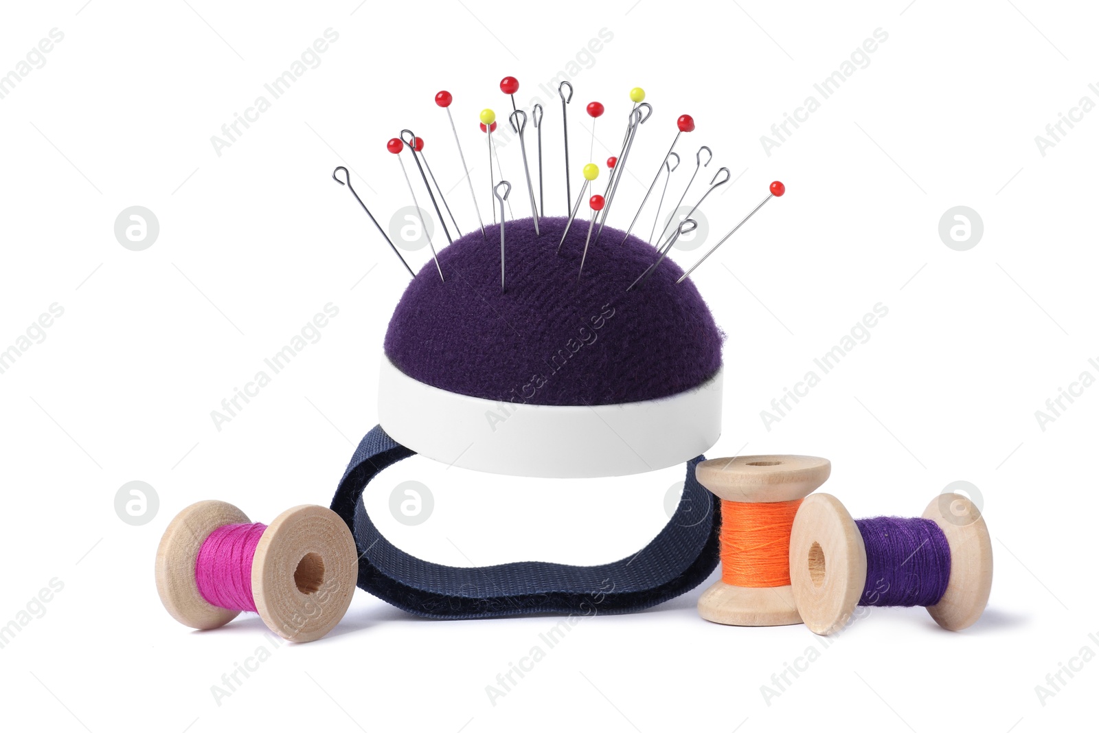 Photo of Blue pincushion with sewing pins and spools of threads isolated on white