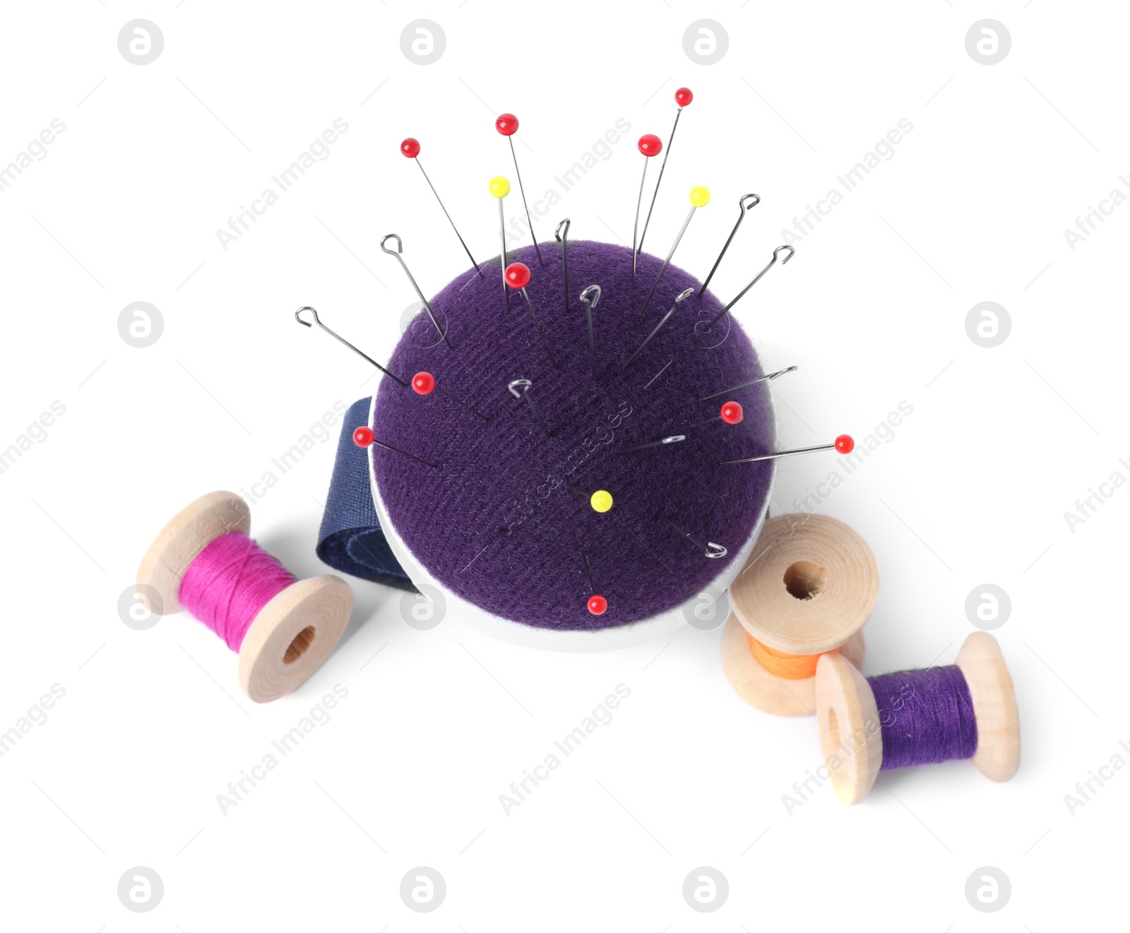 Photo of Blue pincushion with sewing pins and spools of threads isolated on white, top view
