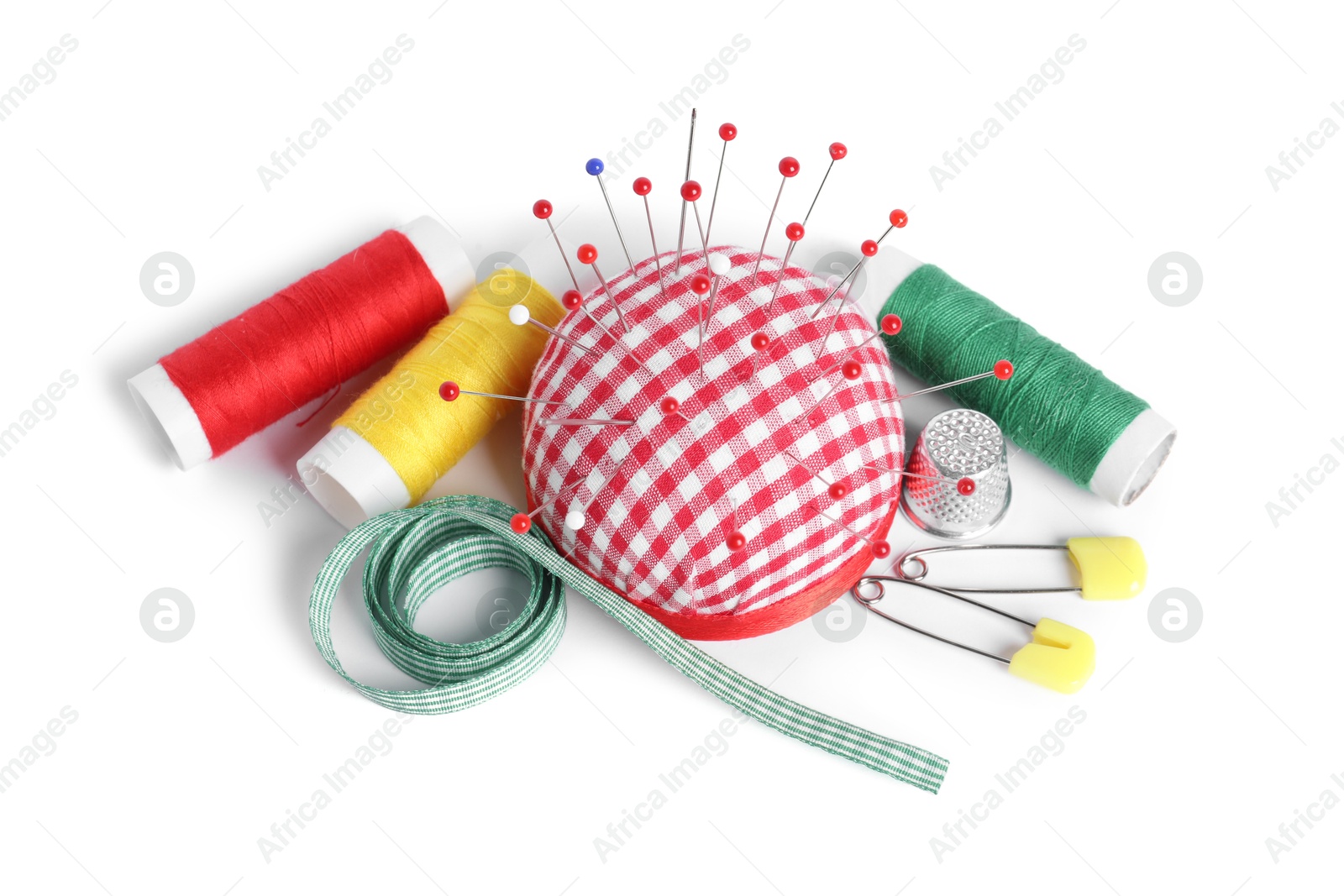 Photo of Checkered pincushion with sewing pins, spools of threads, ribbon and thimble isolated on white, above view