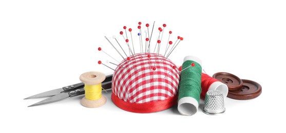 Photo of Checkered pincushion with sewing pins, spools of threads, thimble , cutter and buttons isolated on white