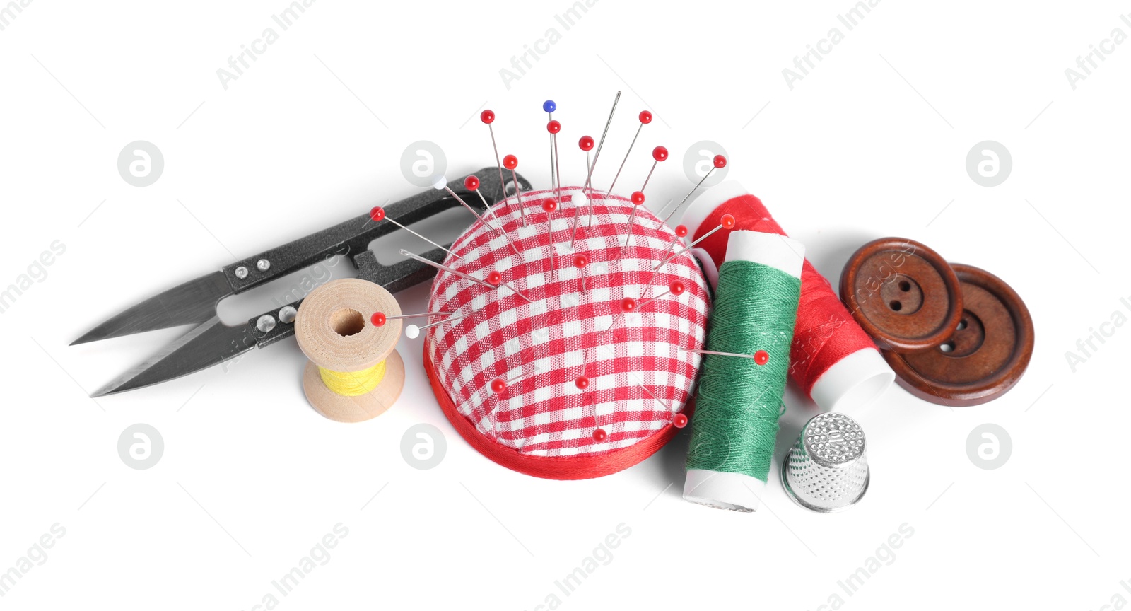 Photo of Checkered pincushion with sewing pins, spools of threads, thimble , cutter and buttons isolated on white, above view