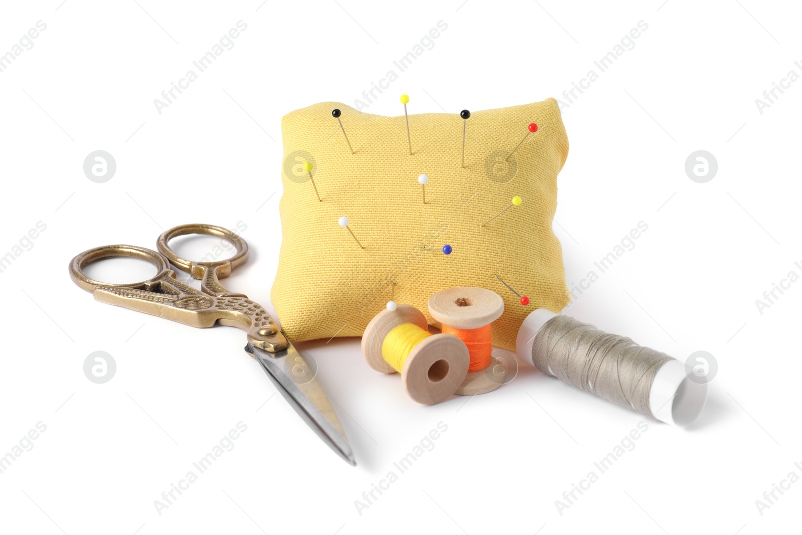Photo of Pincushion, sewing pins, spools of threads and scissors isolated on white