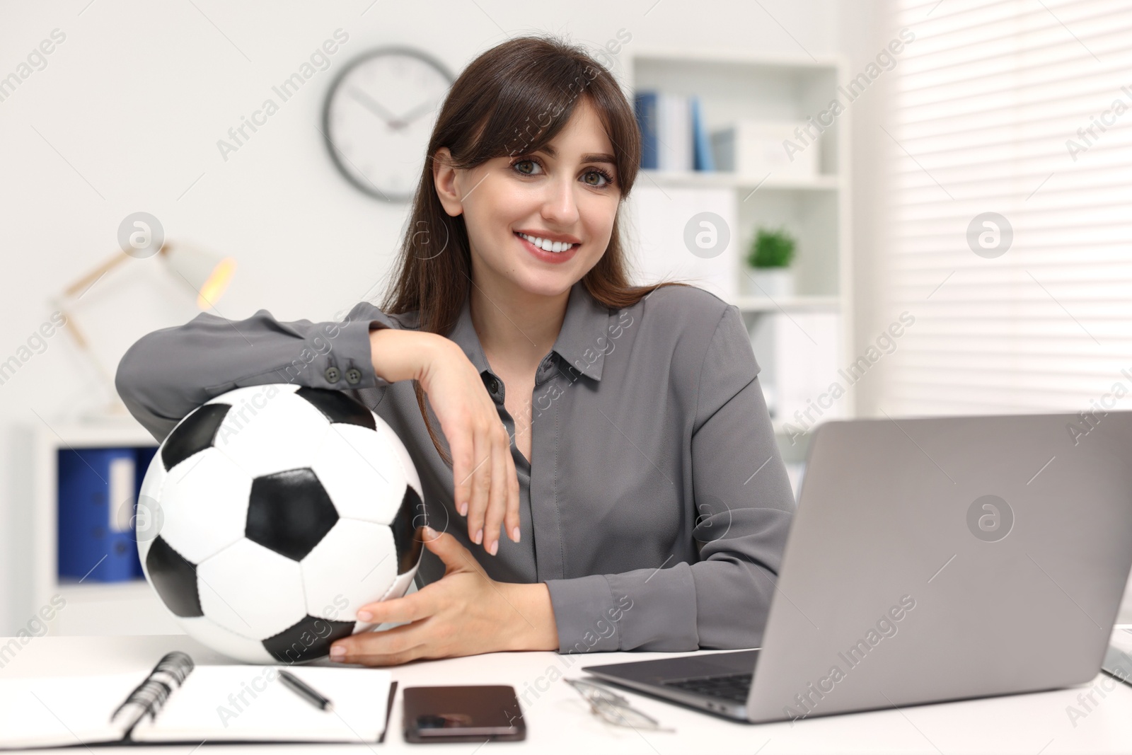 Photo of Smiling employee with soccer ball at table in office