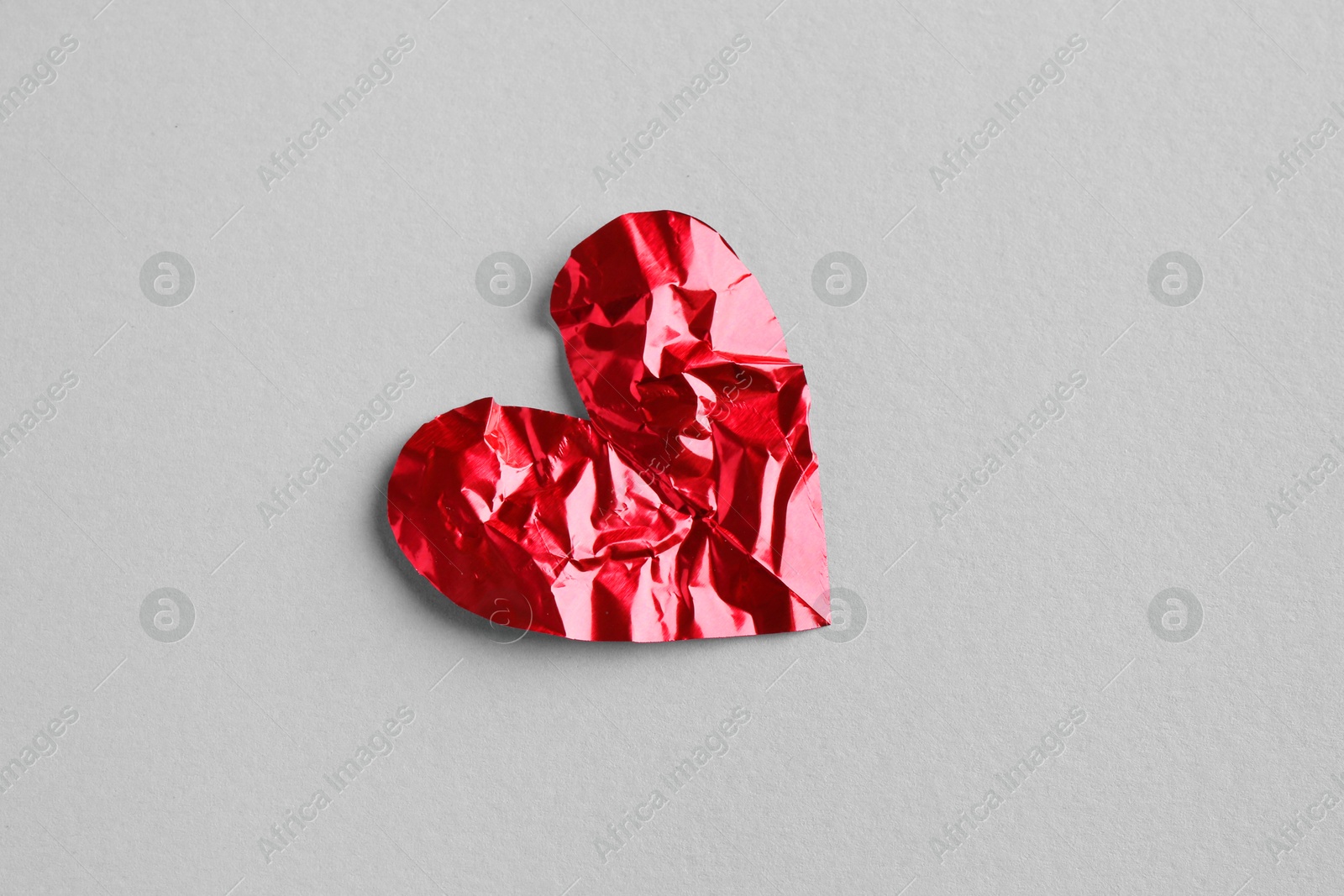 Photo of Red crumpled paper heart on gray background, top view. Breakup concept