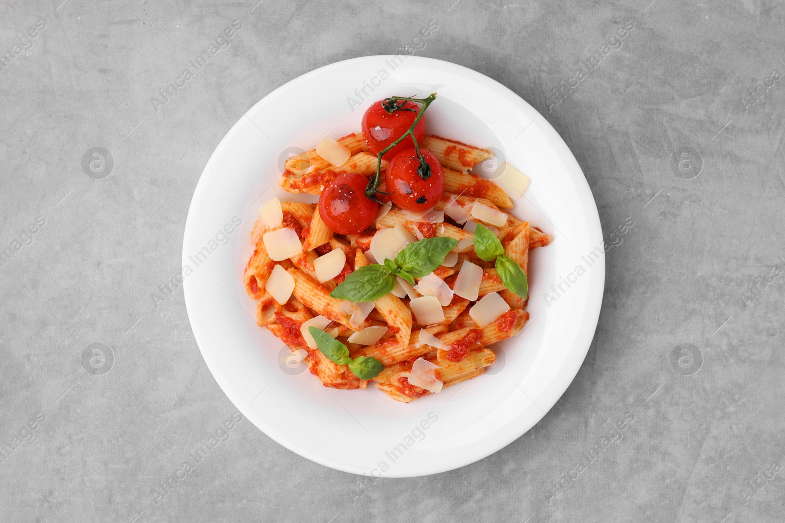 Photo of Tasty pasta with tomato sauce, cheese and basil on grey table, top view