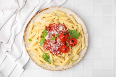 Photo of Tasty pasta with tomato sauce, cheese and basil on white tiled table, top view