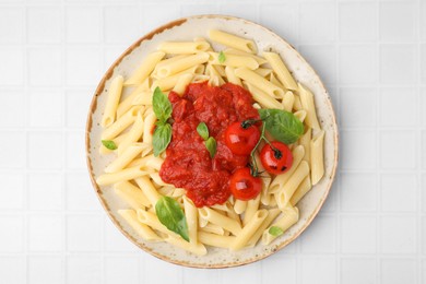 Photo of Tasty pasta with tomato sauce and basil on white tiled table, top view