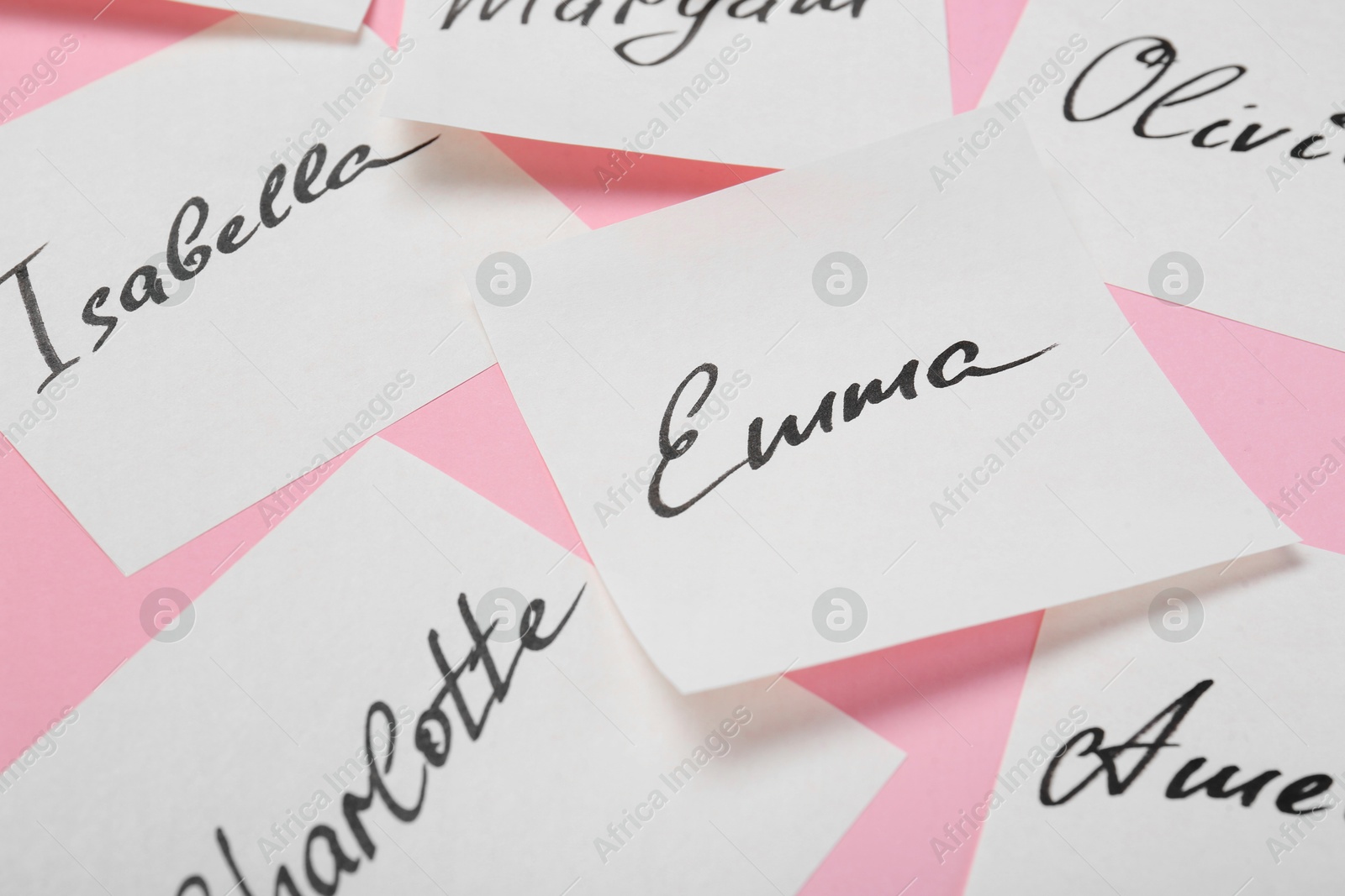 Photo of Paper stickers with different names on pink background, closeup. Choosing baby's name