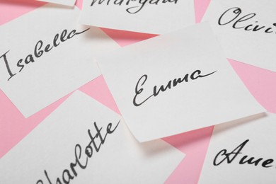 Paper stickers with different names on pink background, closeup. Choosing baby's name