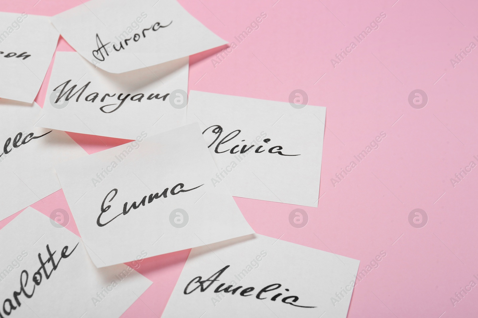 Photo of Paper stickers with different names on pink background, closeup and space for text. Choosing baby's name