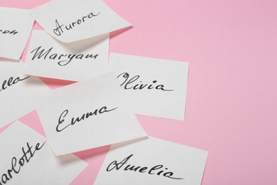 Photo of Paper stickers with different names on pink background, closeup and space for text. Choosing baby's name
