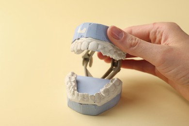 Photo of Woman holding dental model with gums on yellow background, closeup. Cast of teeth