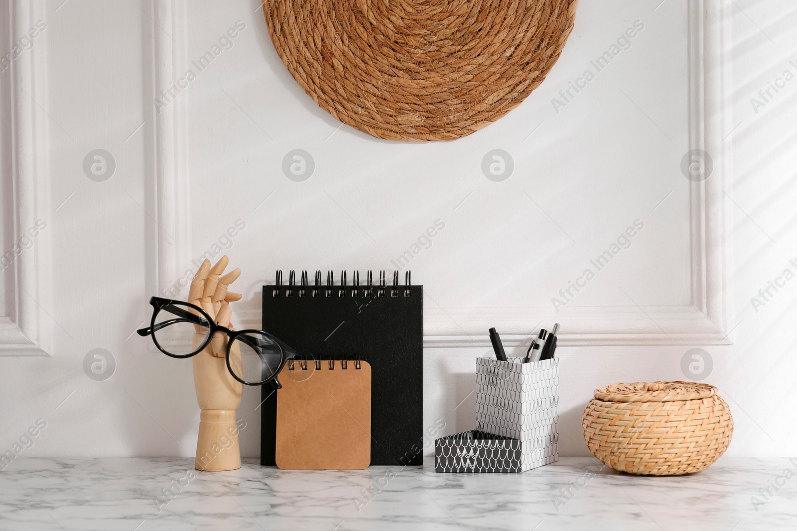 Photo of Stylish office workplace. Decor elements, glasses and stationery on marble table near white wall