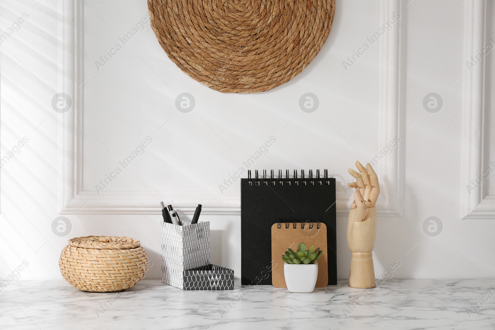 Photo of Stylish office workplace. Decor elements, houseplant and stationery on marble table near white wall