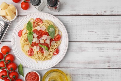 Photo of Tasty pasta with tomato sauce and ingredients on white wooden table, flat lay. Space for text