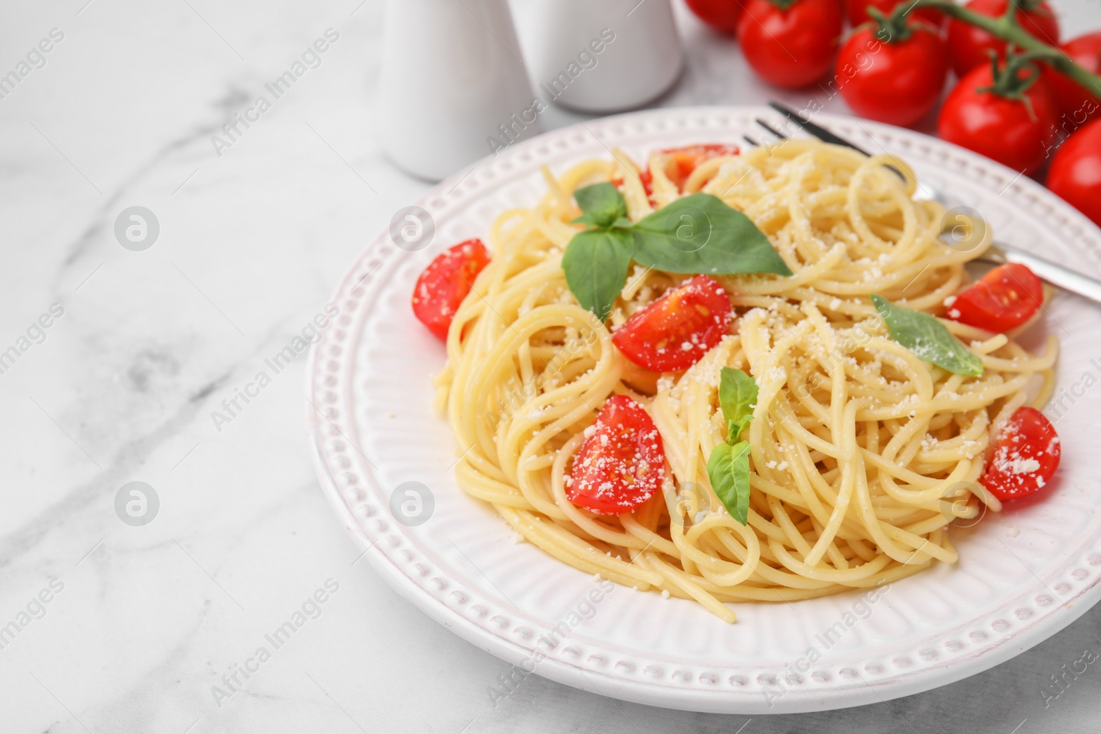 Photo of Tasty pasta with tomato, cheese and basil on white marble table, closeup. Space for text