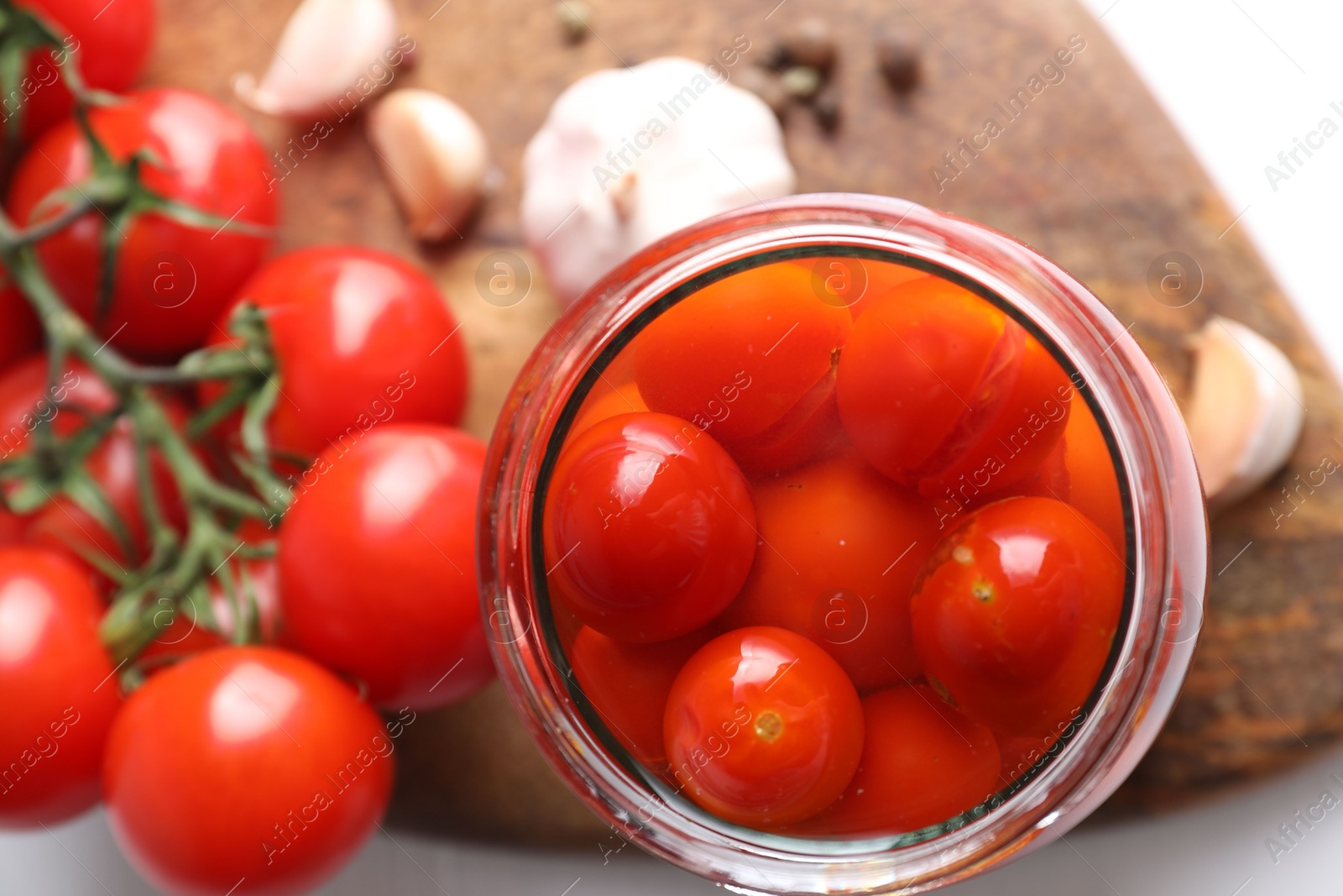 Photo of Tasty pickled tomatoes in jar, fresh vegetables and spices on table, top view