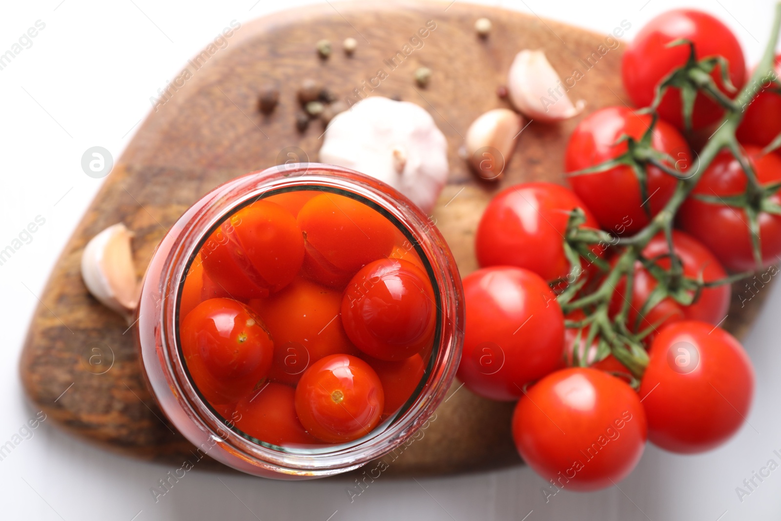 Photo of Tasty pickled tomatoes in jar, fresh vegetables and spices on white table, top view