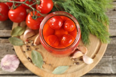 Photo of Tasty pickled tomatoes in jar, fresh vegetables and spices on wooden table, top view