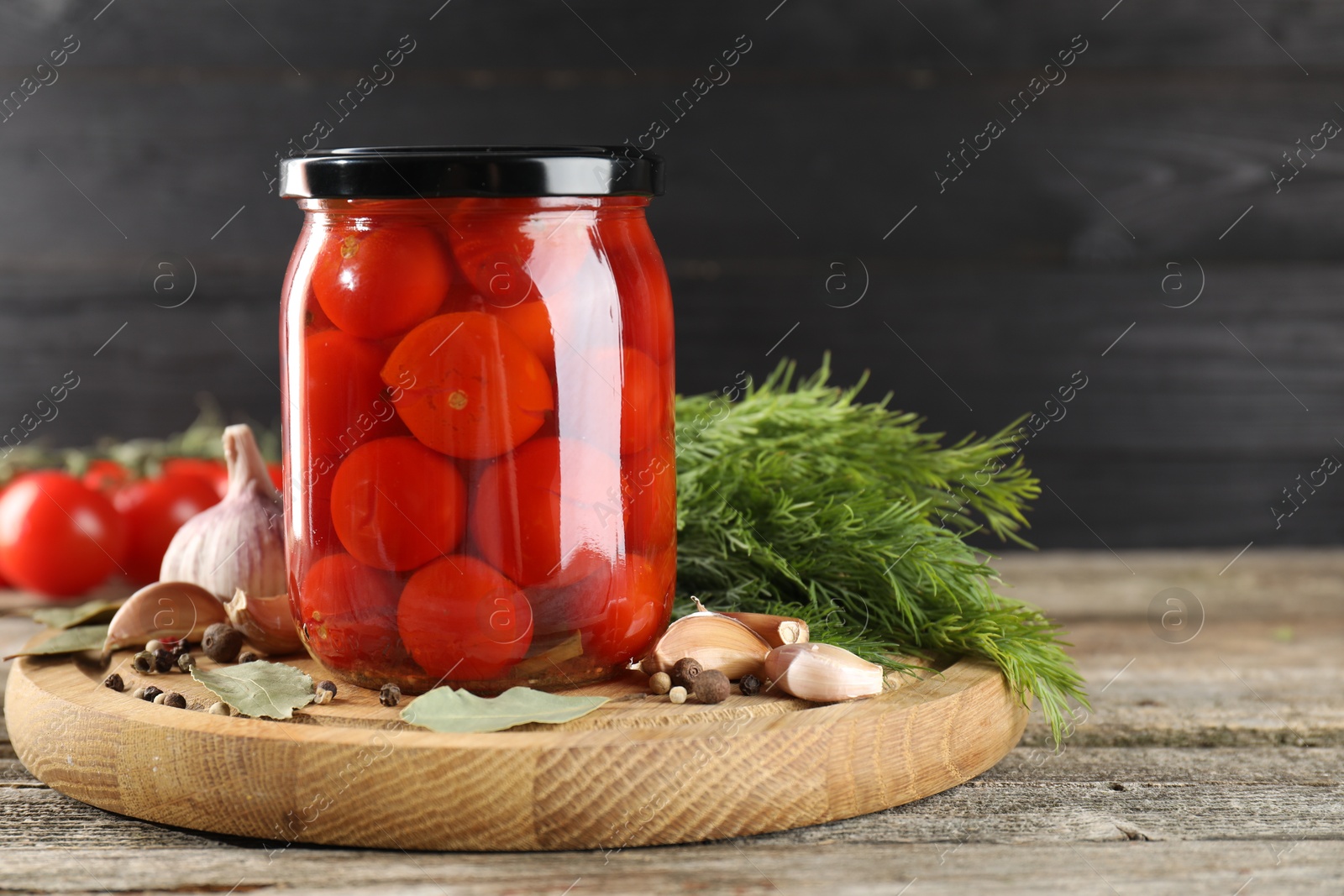 Photo of Tasty pickled tomatoes in jar and spices on wooden table. Space for text